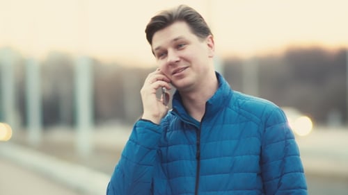 Um jovem usa um telefone celular ao pôr do sol na cidade