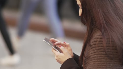 Young Attractive Woman Is Using a Smartphone in a Big City at Sunset