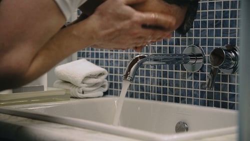 Crop Man Washing Face in Sink