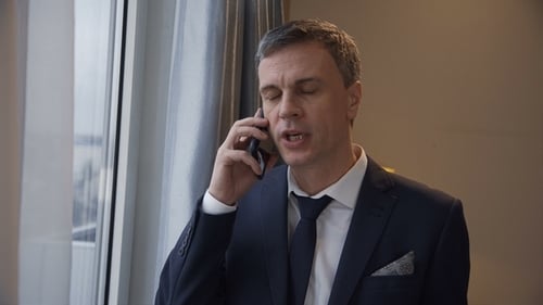 Mann im Anzug telefoniert zu Hause