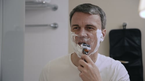 Homem adulto fazendo a barba no banheiro