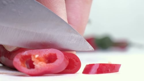 Red Pepper Being Sliced with Knife on White Surface