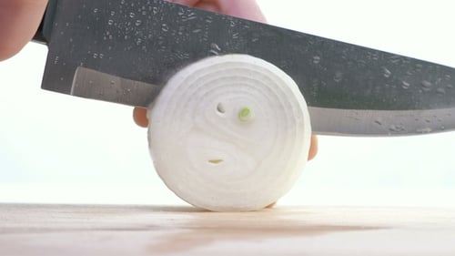 Slicing White Onion with Sharp Knife on Board