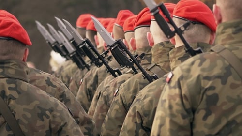 Soldaten in roten Baskenmützen mit Waffen stehen mit dem Rücken zur Kamera. Verleihung der Medaillen