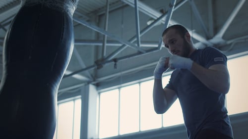 Focused Man Punches Heavy Bag in Gym