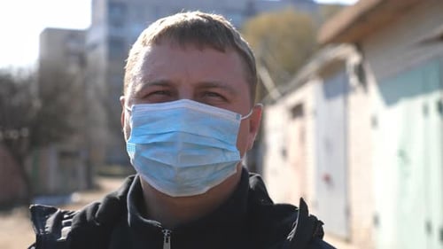 Portrait of Man with Medical Face Mask Stands at City Street During COVID-19 Epidemic. Guy Wearing
