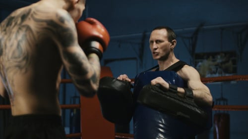Young Shirtless Man Boxing in Gym with Trainer
