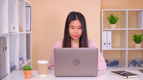 Young Adult Woman Works at Desk with Laptop