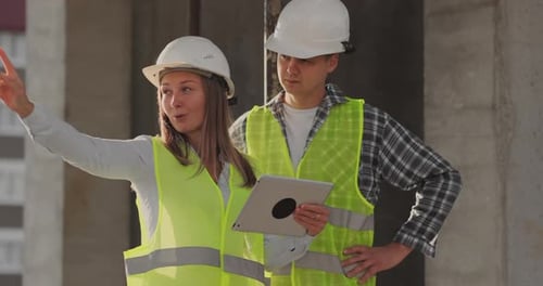 Construction Site Team or Architect and Builder or Worker with Helmets Discuss on a Scaffold