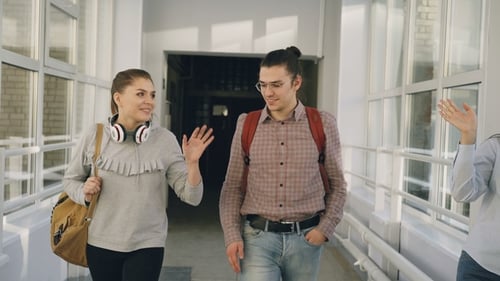 Two Female and Male Students Are Walking in University Hall Discussing Something. They Meet Friends