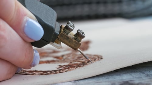 Woman Uses a Device for Burning on Natural Leather. Creating and Decorating of Handmade Wallet or