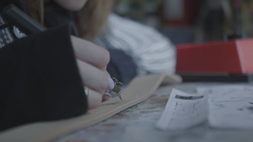 La mujer usa un dispositivo para quemarse en cuero natural. Creación y decoración de billeteras hechas a mano