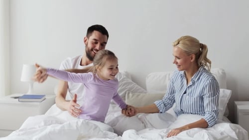 Family Fun: Child Jumps on Bed with Parents