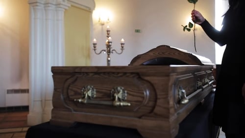 Woman Places Red Rose on Wooden Coffin