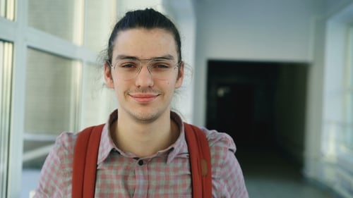 Smiling Young Adult Wearing Backpack in Hallway