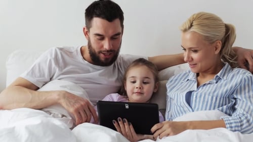 Happy Family Using Tablet Together in Bed