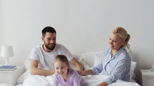 Happy Family Playing on Bed Together