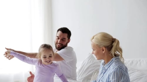 Happy Family Playing Together on Bed at Home