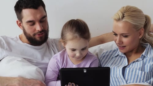 Happy Family Using Tablet Together in Bed