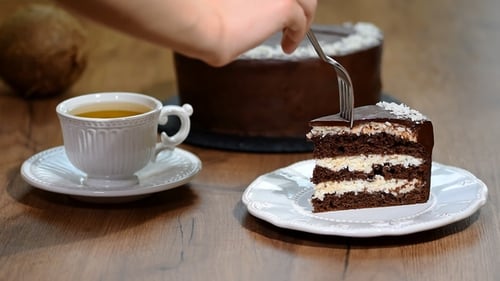 Cutting into a Chocolate Cake with Tea