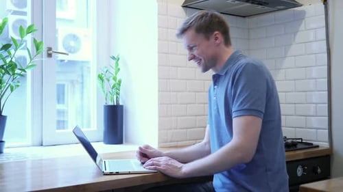 Man Using Laptop For Video Conference in Kitchen