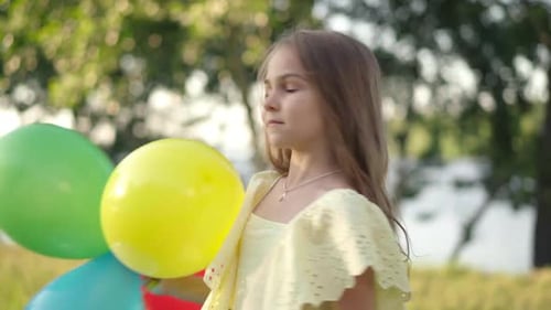 Back View Playful Girl with Balloons Turning to Camera Laughing Grimacing Outdoors
