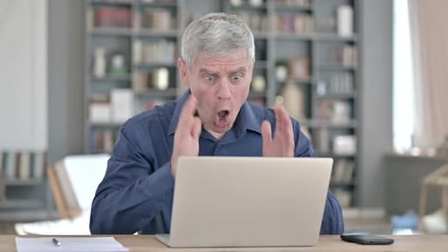 Shocked Man Reacting To Failure While Working on Laptop in Office