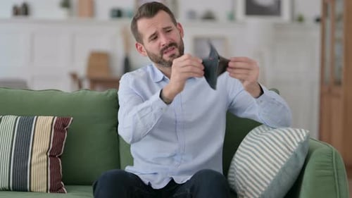 Pleite Junger Mann checkt leere Brieftasche auf Sofa