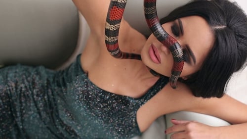 Portrait d'une fille modèle avec un serpent sur un canapé