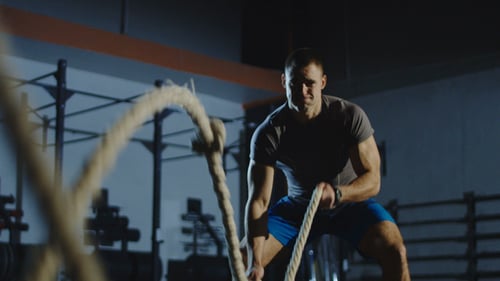 Athletic Man Working Out with Ropes in Gym