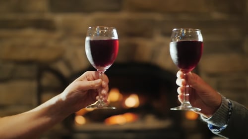 Buvez du vin près de la cheminée. Deux mains féminines tintent des verres de vin rouge