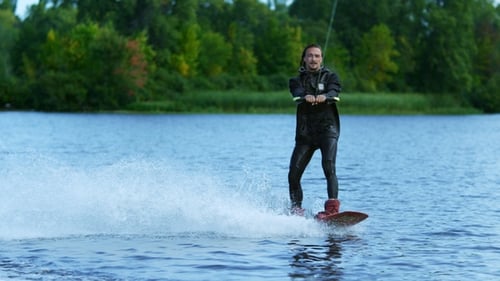 Joven montando wakeboard en el lago de verano. Hombre disfrutando de vacaciones extremas