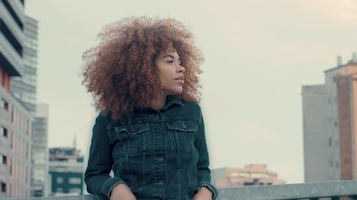 Mujer negra de raza mixta con gran pelo afro rizado en la ciudad al aire libre