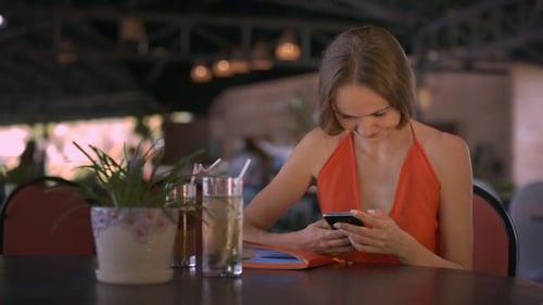 Woman Using Phone at Outdoor Cafe