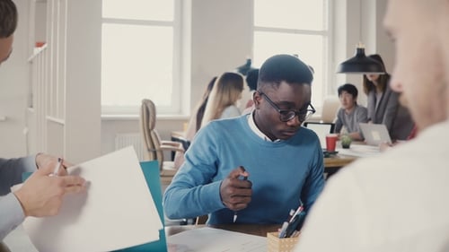 Jeune homme afro-américain concentré travaillant dur sur une Sketch d'architecture avec des collègues dans
