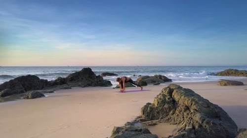Woman Practices Yoga on Sea Sand Beach at Sunrise