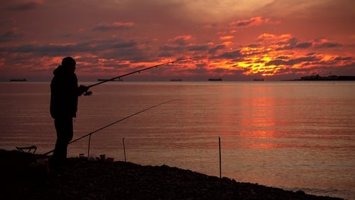 Lone Fisherman Silhouette at Colorful Sunrise on Coast
