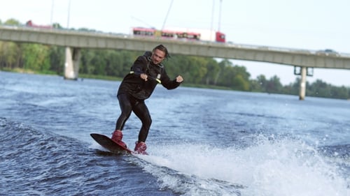 Hombre alegre haciendo wakeboard en City River. Entretenimiento extremo en el agua