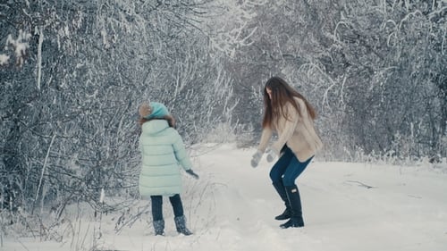 Mama und Tochter werfen Schneebälle