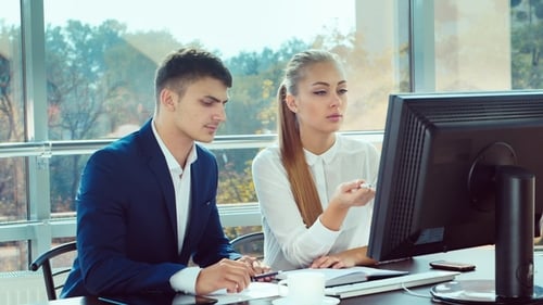 Two Young Men Working in the Office. Together They Look at the Computer Monitor