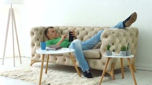 Man Relaxes on Couch Using Tablet at Home