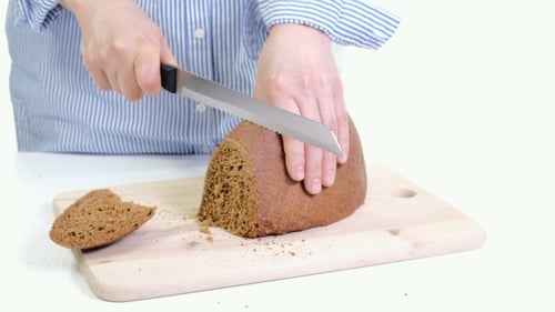 Hands Slicing Dark Rye Bread on Cutting Board