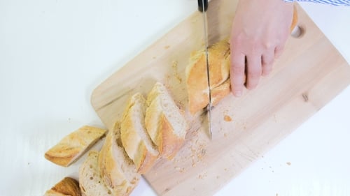 Slicing Crusty Baguette on Wooden Cutting Board