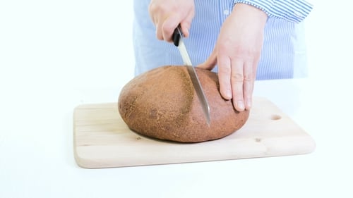 Woman Cutting a Loaf of Brown Bread