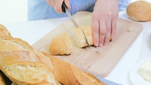 Slicing Baguette Bread With Sharp Knife on Board