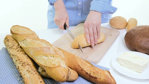 Person Cuts Bread on Cutting Board for Meal