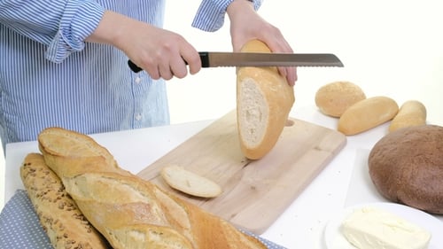 Fresh Bread Slice and Cutting Knife on Rustic Table. With Wooman Hands