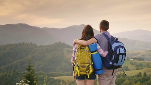 Couple with Backpacks Enjoying Mountain View at Sunset