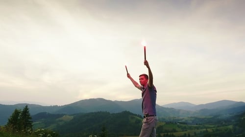 Young Man Celebrates with Flares on Mountain