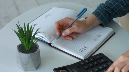 Person Writes in Schedule Book with Pen
